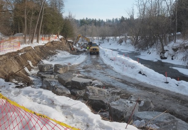 construction crew reinforcing the banks of the Highland creek with large rocks, winter, 