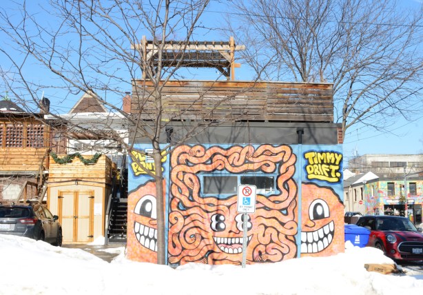 mural of many faces with big mouths and white teeth