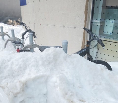 bike parked, almost totally covered by a snow bank