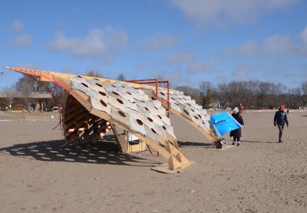 a woman with blue paper? beside art installation designed by Evan Fernandes, Kelvin Hoang, Alexandra Winslow, Justin Lieberman & Ariel Weiss, Lead by Associate Professor Vincent Hui from Ryerson 