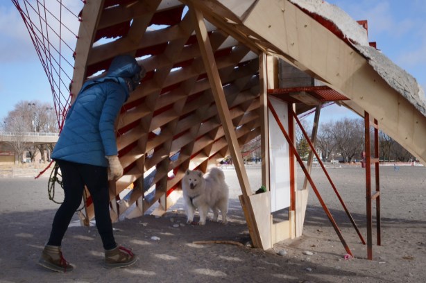 a woman and a dog on the beach, under the overhang of an art installation, S'winter station,