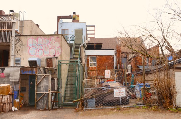 Toronto downtown alley backs of houses, exterior stairs up to third floor, fences, brick, concrete, 