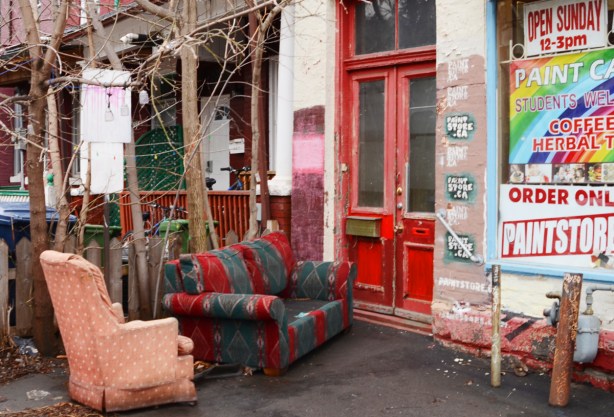 loveseat and armshair outside on grey mat, door to building is double red door, storefront, 