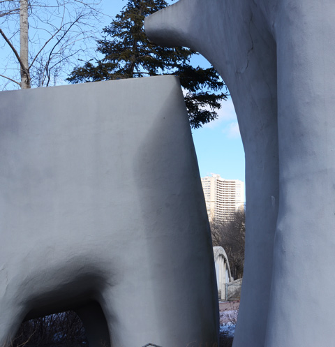 large container on right with spout to concrete planter on the left, in the background, seen between the two concrete planters, an old cement bridge and a highrise apartment in the distance