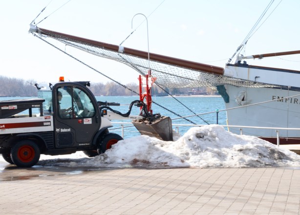 a front end loader removes snow from the waterfront, with the Empire Sandy, boat, parked right beside 
