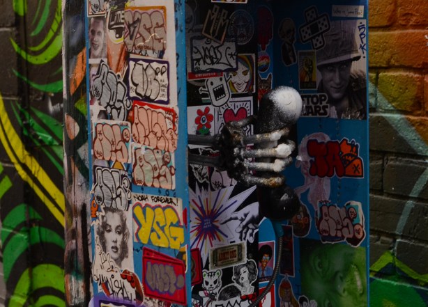 Bell phone booth covered with stickers, plus a fake bony hand holding onto the receiver, in Graffiti Alley
