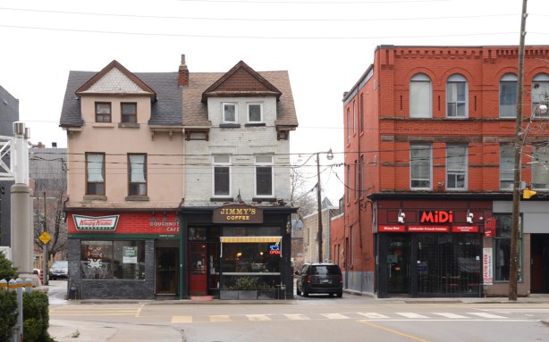 old buildings on McCaul street, two remaining rowhouses, three storeys, one is Krispy Kreme at street level, the other is a Jimmys Coffee. A larger squarer brick building on the right, also three storeys