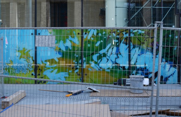 behind construction fence, coloured glass ready to install inside a new office building