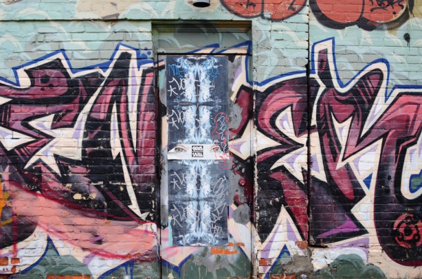 jumblefacefoto collage paper pasteup on door in graffiti alley in the middle of a text throw up street art 