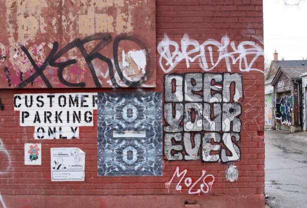 brick wall with paper pasteup graffiti, open your eyes, a jumblefacefoto 