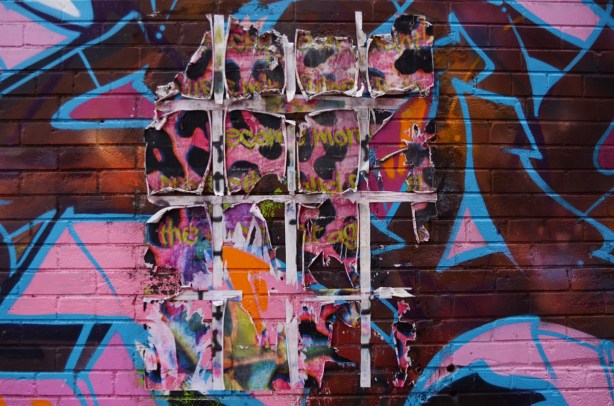 grid of painted paper on top of street art, peeling at edges