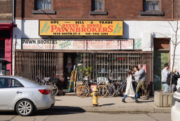 Pawkbrokers shop on Queen East, metal grille covering windows, people walking past, 
