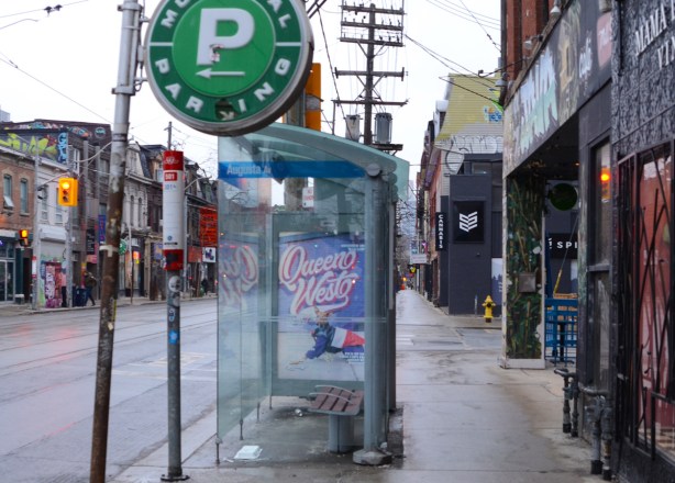 sidewalk scene on Queen West, bus shelter with Queen West advert, green P parking sign, some stores, 