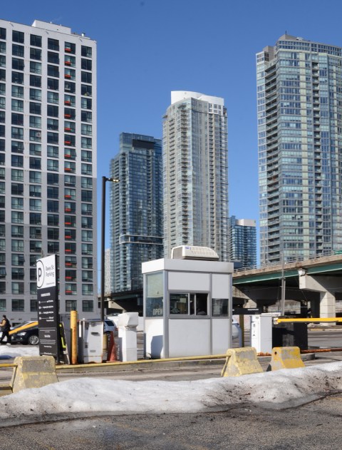 parking booth at parking lot on northwest corner of Rees and Queens Quay, tall condos and aprtments in the background, also the Gardiner Expressway