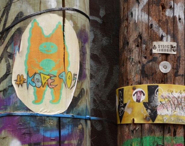 kode 905 slap graffiti little orange character with green face and tummy, on a pole