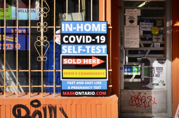 signs in the window of a convenience store, covid test, pregnancy tests, in home self test, 
