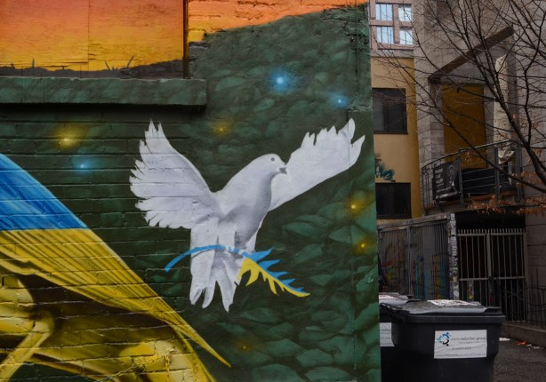 part of a mural, white dove of peace with a branch in its claws that is half blue and half yellow representing Ukraine