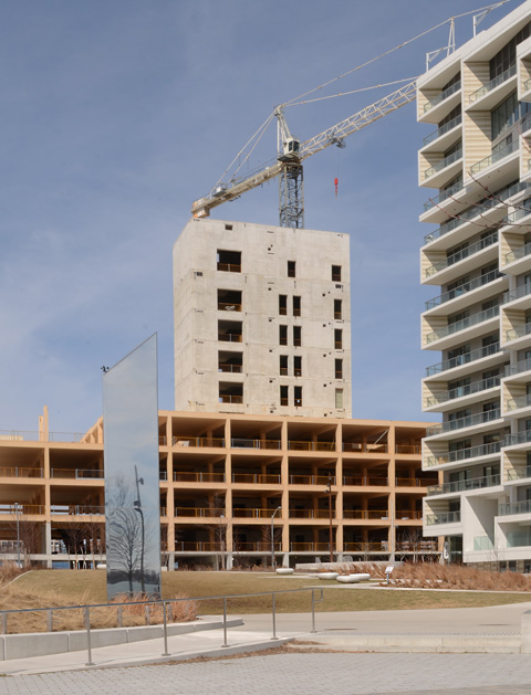Aitken Park in front, new condo building built behind it, concrete core but rest built of wood