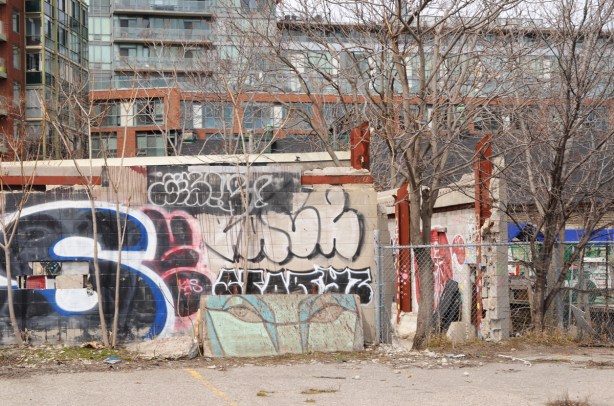 old anser eyes graffiti on a piece of concrete leaning against a fence 