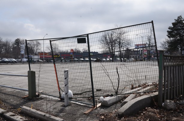 crooked metal fence around a vacantlot that has been paved over, yonge street, about to be redeveloped