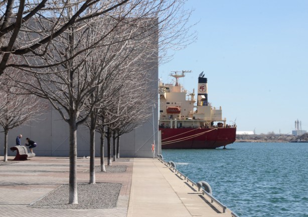 Toronto waterfront, public path ends at a large high concrete wall by Redpath Sugar, the back end of a red ship is visible jutting out from behind the wall 