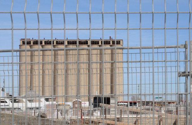 concrete silos in background, construction fence in front, 