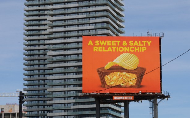 large billboard in front of tall condos, a sweet and salty relationship, reeses peanut butter cups with potato chips