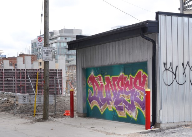 text throw up street art on a garage door, with construction site behind