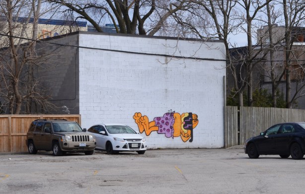 on a white wall, a painting of Garfield the cat lying down with sunglasses and purple polka dot shorts on