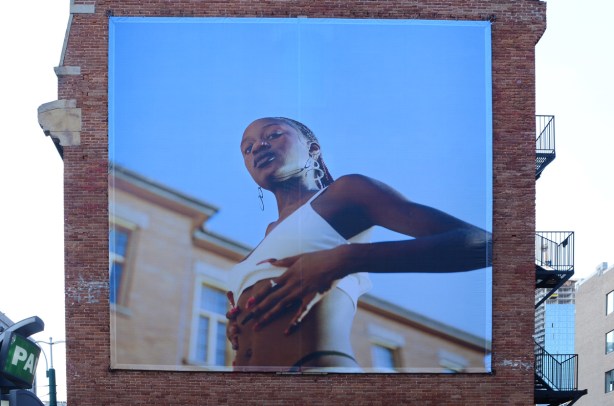 very large photo titles Georgia, pasted on brick wall, black woman rubbing her tummy, 