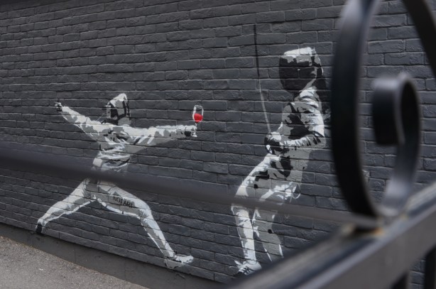 mural of two fencers, one with a glass of red wine in their hand