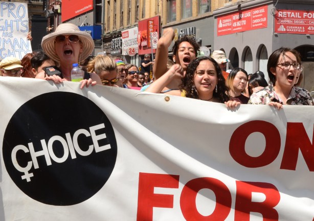 women holding banner for ontario coalition for abortion clinics, pro choice, dyke march 2022