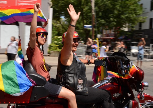 two women on motorcycle waving to crowd