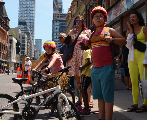two kids in bike helmets that say love is love watching dyke march