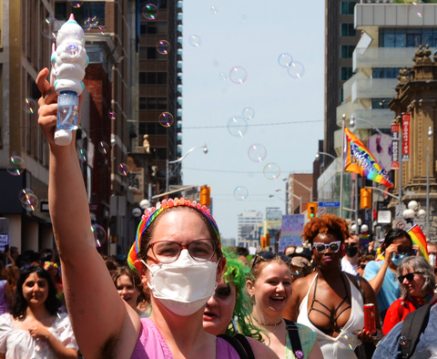 woman wearing mask and blowing bubbles in dyke march