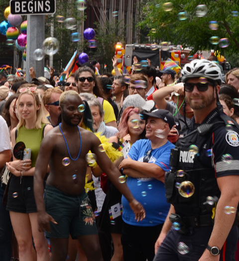 policeman and crowd at pride, lots of bubbles in the air 