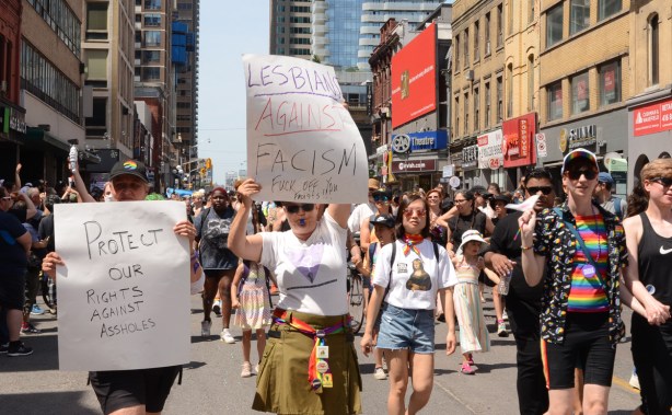 people holding protest signs in dyke march, keep lesbians safe from fascists