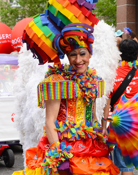 person in costume at pride parade, hair wig made of ribbons, big puffy skirt, ribbons in curls as collar