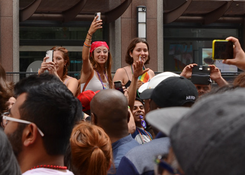 women cheering and taking photos while watching pride parade