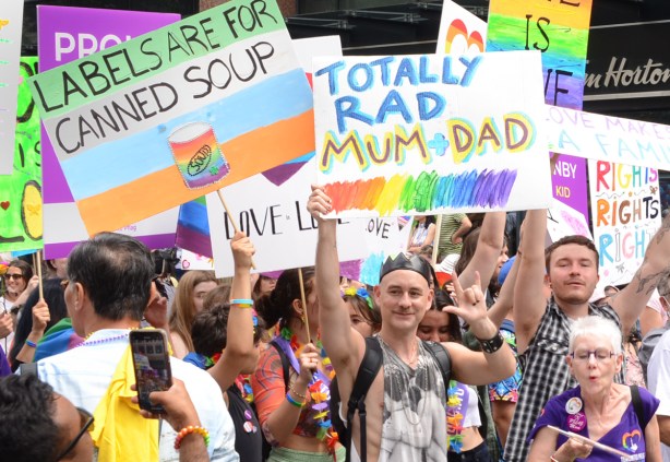 people with signs at pride parade, pflag group, totally rad mum and dad, labels are for canned soup, love is love