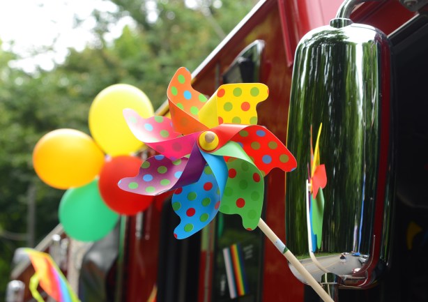little colourful plastic windmill attached to mirror of firetruck, also 2 yellow balloons and 1 green balloon
