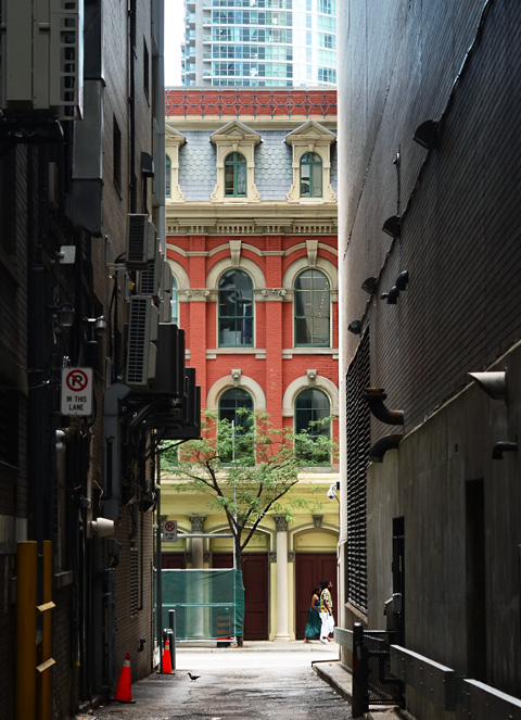 looking down a narrow alley to the old brick building on the next street 