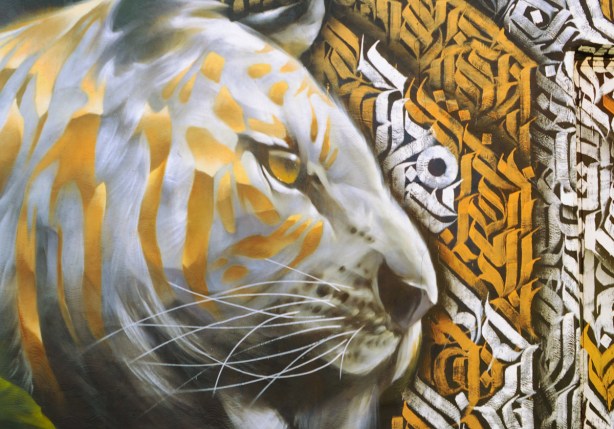 mural, part of, a large cat's head in silver and gold with long whiskers and a gold coloured eye
