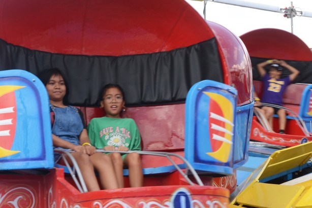 a young girl and her mother spinning in a red round pod at ride at cne