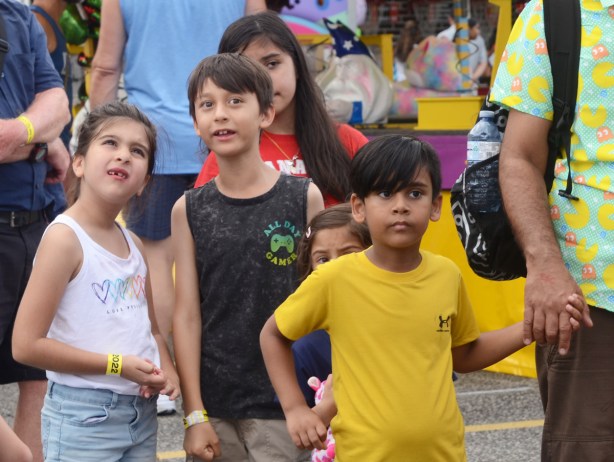 young kids at the cne midway watching people on rides, looking up