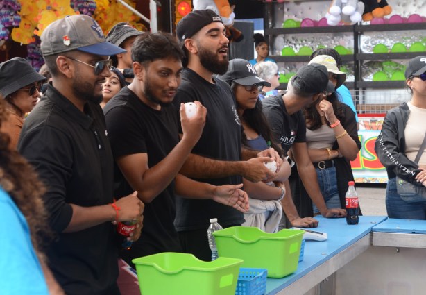 young men dressed in black lined up along a counter, ball toss game at cne