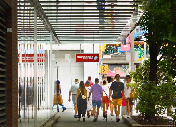 pedestrians on sidewalk on Lower Jarvis with reflections in window beside and overhang above at Shoppers Drug Mart