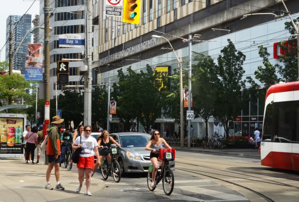 intersection of Bay and Dundas, westbound traffic and bikes, some pedestrians ready to cross Bay as well. 
