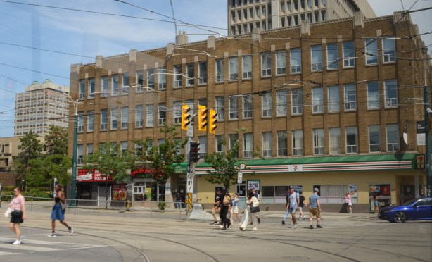 northeast corner of Spadina and College streets, people crossing Spadina, low rise old brick building