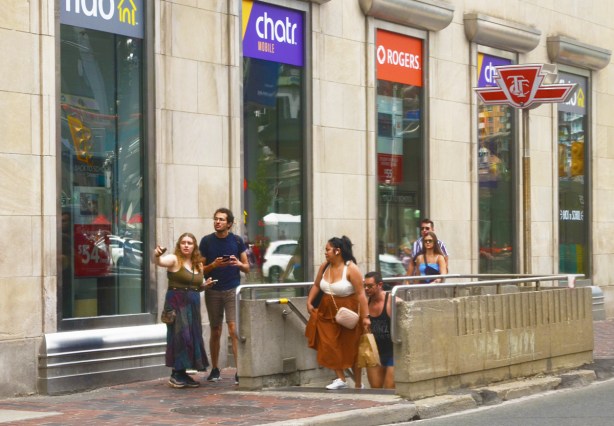 people exiting Dundas subway station on the northwest corner of Dundas and Yonge, a couple trying to figure where they are